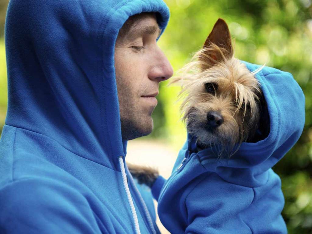 Man in blue hoodie holding small dog, also wearing blue hoodie