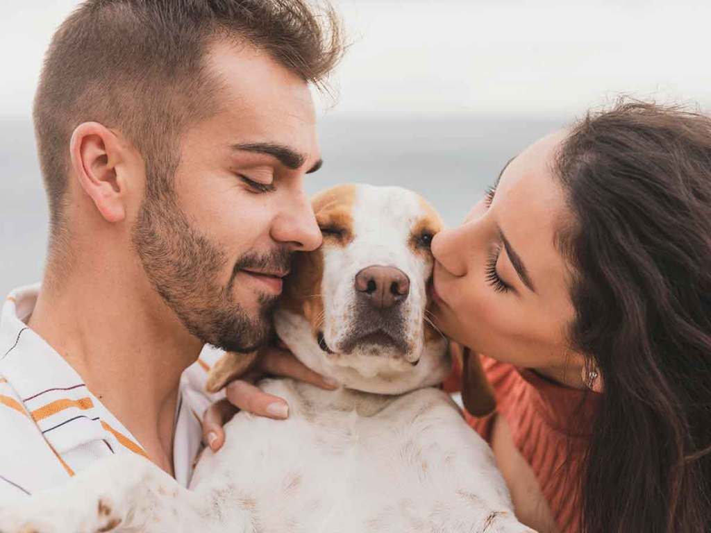 Woman and man kissing their dog in between them