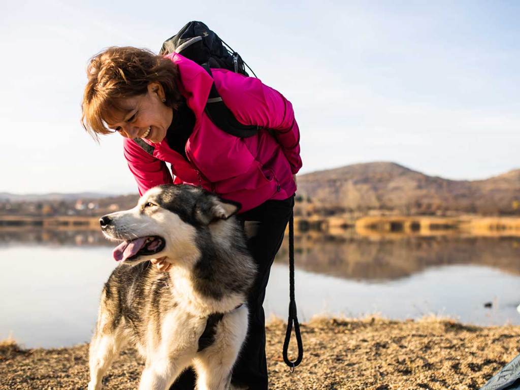 Pet owner smiling and petting her husky during a walk